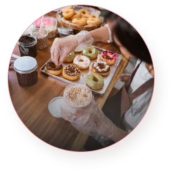 A hand sprinkles raisins on a donut